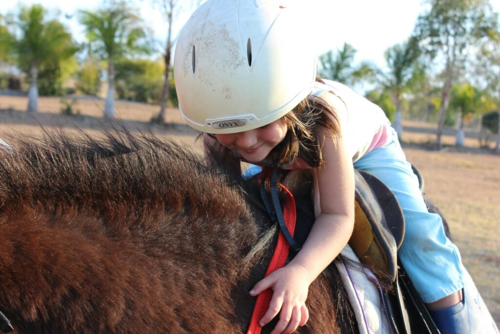 Young girl smiling while horseback riding with helmet outdoors in sunny Australia.